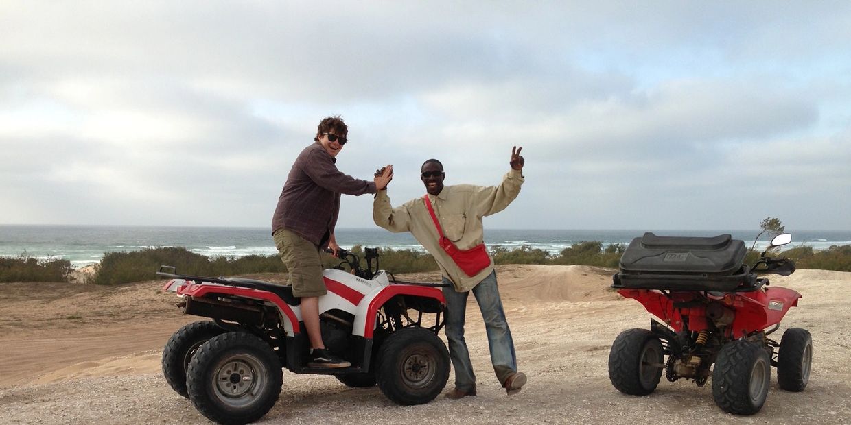 Jared high-fiving a friend while on ATVs at the beach